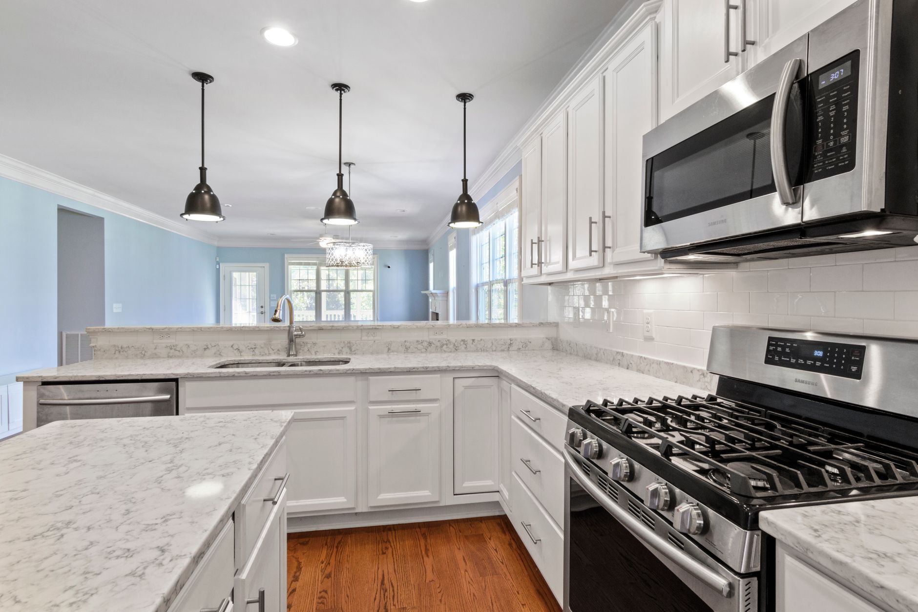 Sleek kitchen featuring stainless steel appliances and marble countertops under pendant lighting in Hendersonville, NC